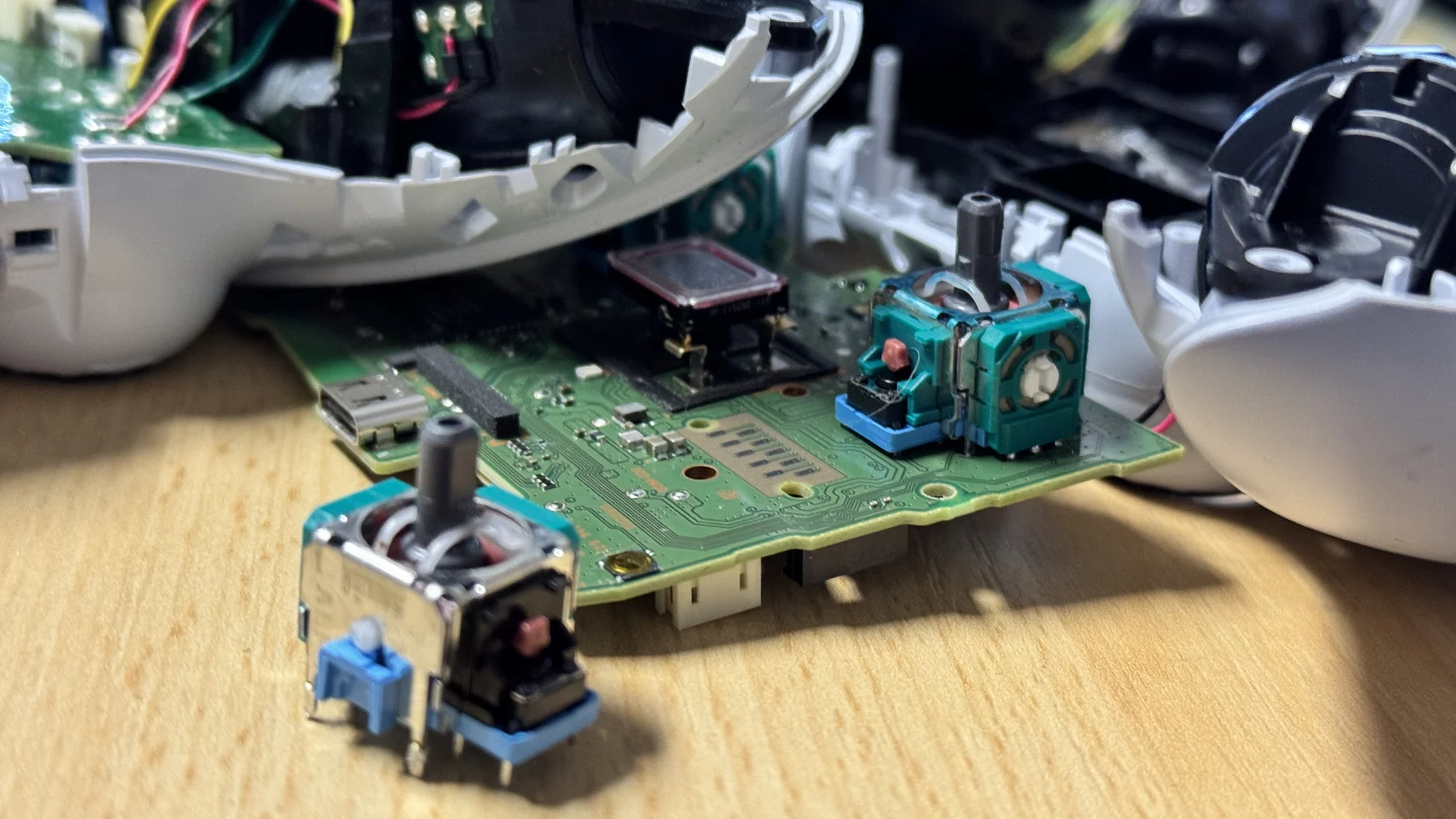 Detail analogových joysticků na desce rozebraného ovladače při opravě v naší dílně