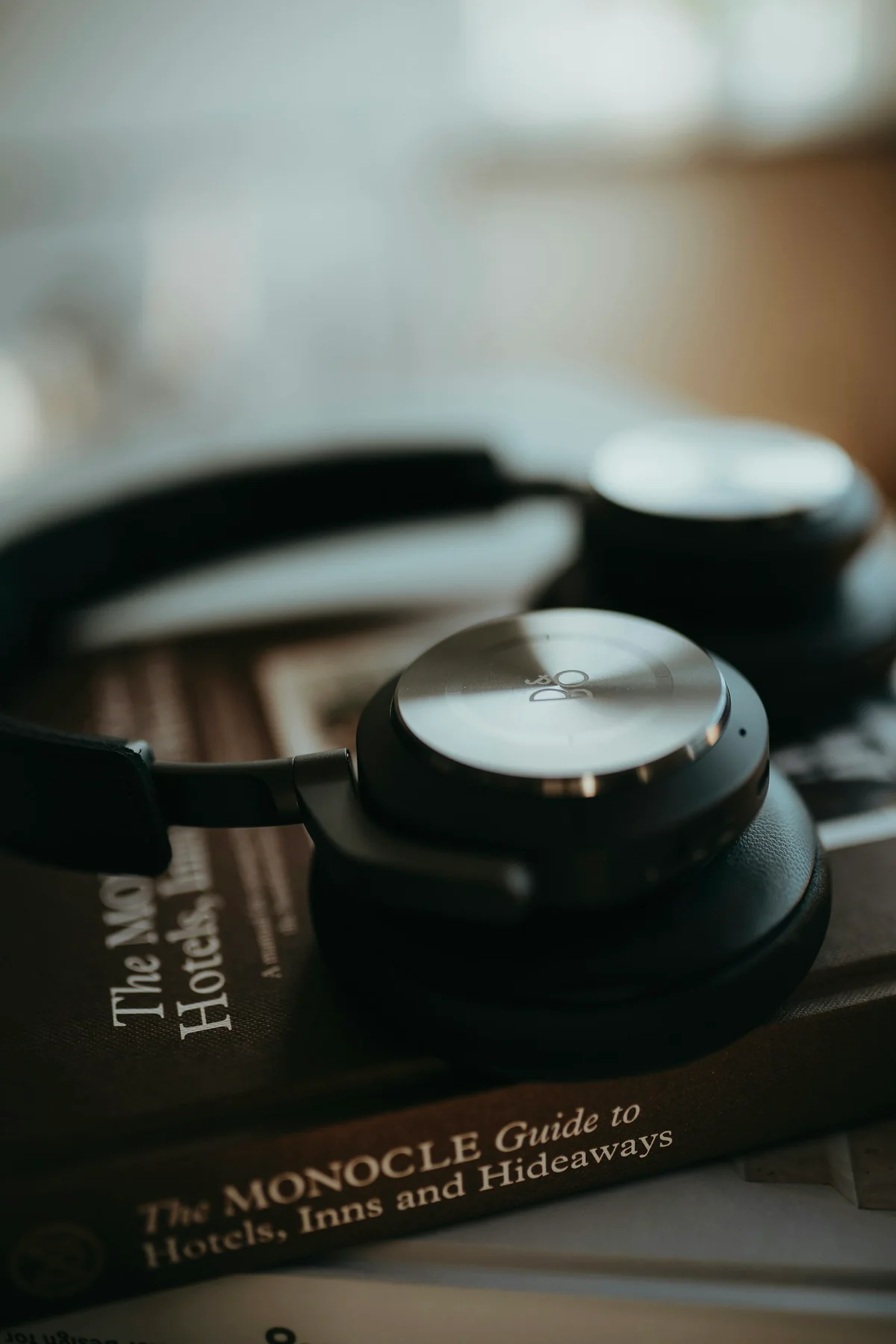 Sluchátka Bang & Olufsen s kovovými mušlemi položená na knihách